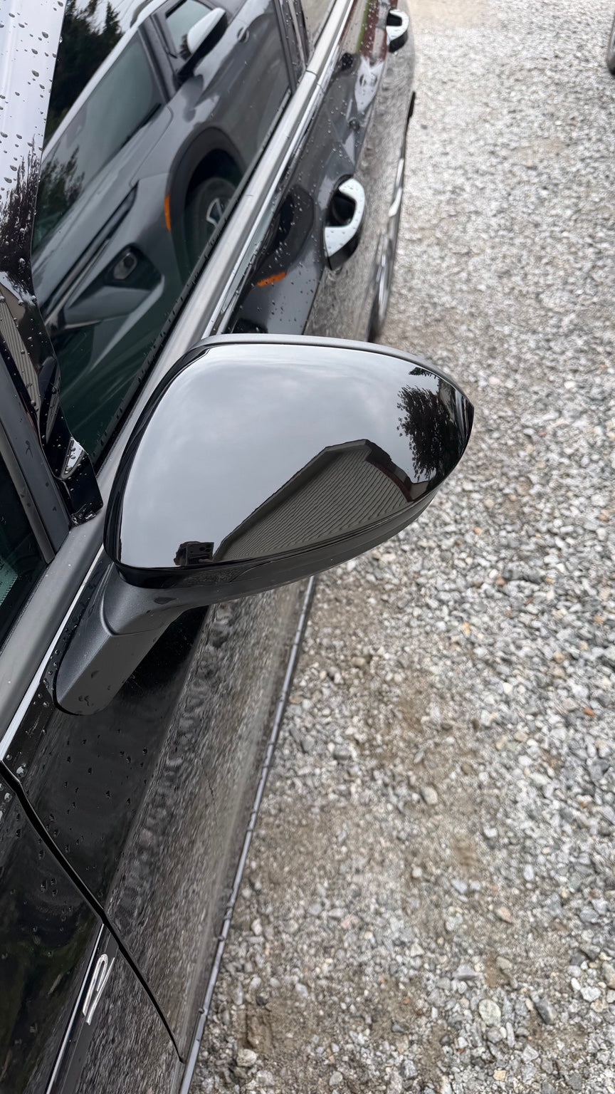 Close-up of gloss black mirror cap fitment on a Volkswagen Golf MK8
